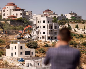 A man watches Israeli bulldozers demolish a Palestinian home in Hebron, in the occupied West Bank
